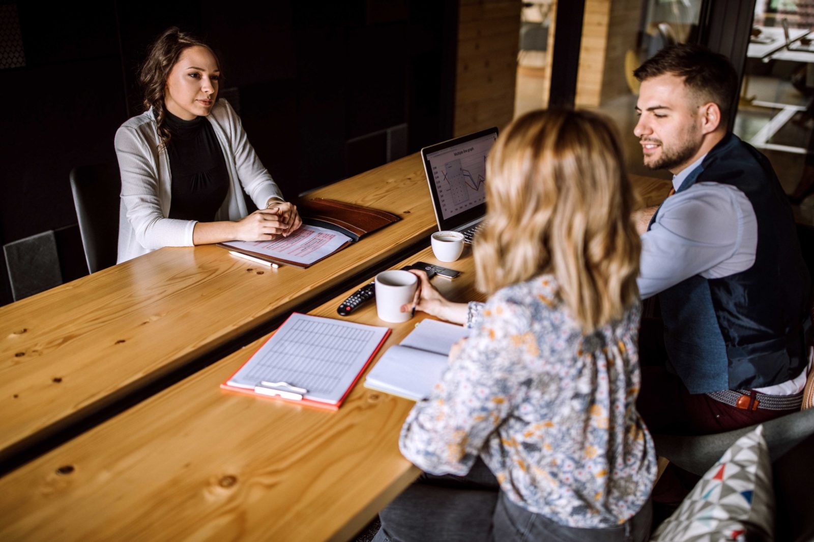 Man accompanied with two women sitting in board room and having business interview